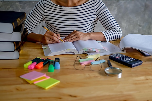 A student using a planner to schedule study sessions for multiple AP exams. The planner is filled with notes, highlighting exam dates and study goals, with different colored highlighters.