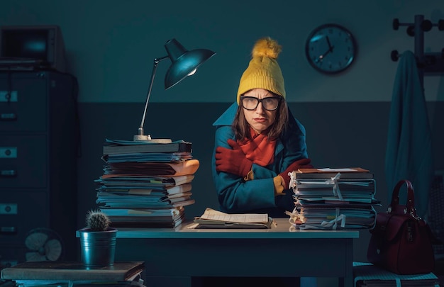 A student sitting at a desk, surrounded by books and papers, deeply immersed in writing an essay. The scene is illuminated by a desk lamp, casting a warm glow on the student's focused face. A laptop is open in front of them, displaying a word processing document, and a steaming mug of coffee sits nearby.
