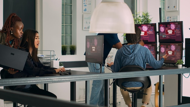 A data scientist working at a computer, surrounded by multiple monitors displaying complex data visualizations and code. The environment is a modern office with a collaborative atmosphere.