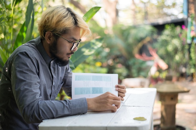 A student looking thoughtfully at two different college brochures, symbolizing the decision-making process regarding credit transfer and accreditation.
