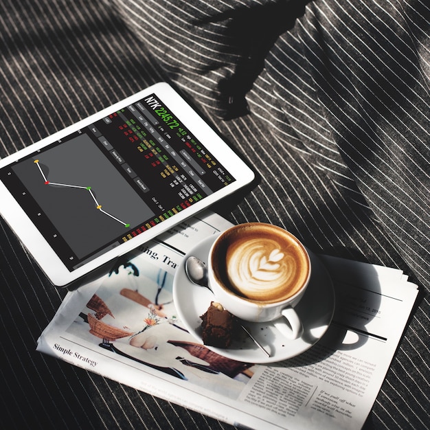 A person looking at a tablet showing stock charts and graphs, with a cup of coffee nearby, symbolizing modern investment strategies and tools.