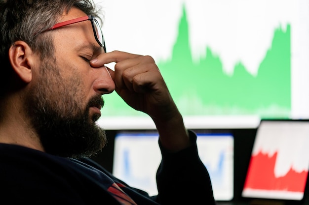 A close-up shot of a stressed investor with hands on their head, looking at a rapidly declining stock market chart on a computer screen, emphasizing the impact of emotional investing.