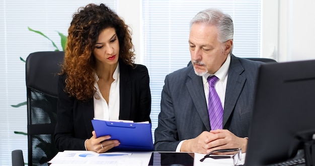 A person signing documents to open a brokerage account with a financial advisor in an office setting.