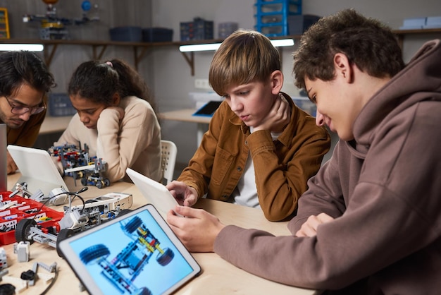 A group of high school students working collaboratively on a robotics project. They are using tools and computers in a well-equipped lab, and their expressions show engagement, excitement, and teamwork. The image conveys the practical, hands-on learning that STEM programs offer.