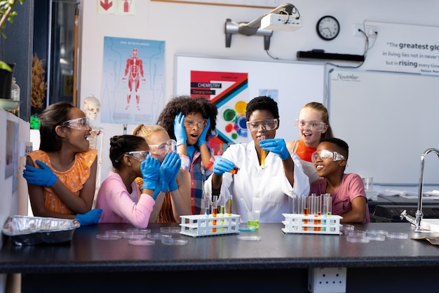 A diverse group of students working together in a science lab, with a teacher supervising and providing guidance. The scene emphasizes hands-on learning.