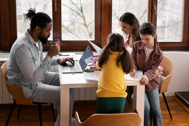 A classroom setting with students working on laptops, collaborating on a group project. The teacher is walking around, providing guidance and support. The atmosphere is focused on collaboration and problem-solving.