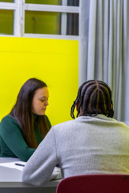 A school counselor speaking with a student in a brightly lit, welcoming office. The counselor is gesturing kindly, and the student appears to be engaged in the conversation, reflecting the importance of mental health support in schools.