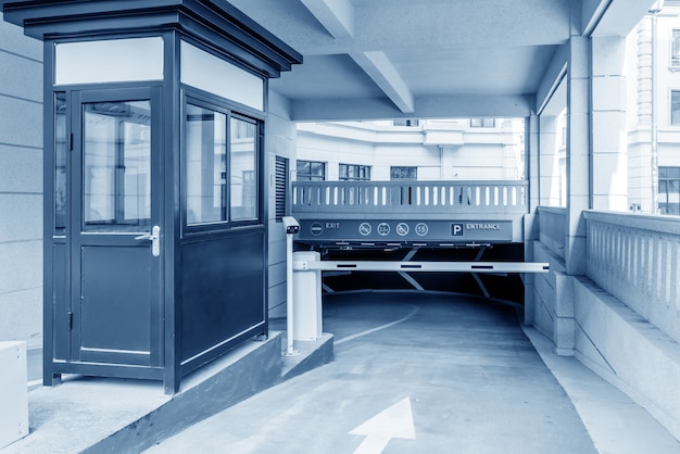 An external shot of a school equipped with advanced security measures, including secured entrances, surveillance cameras, and controlled access points. The scene is on a school day, with students arriving, supervised by school staff.