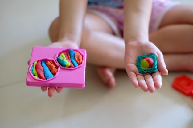 Close-up shot of a child's hands engaged in a sensory activity, such as playing with blocks or modeling clay. The hands are small and chubby, and the activity promotes fine motor skills.