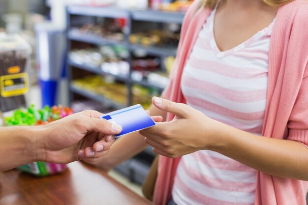A close-up of a person's hands using a credit card at a grocery store checkout, emphasizing the everyday spending that can accumulate rewards.