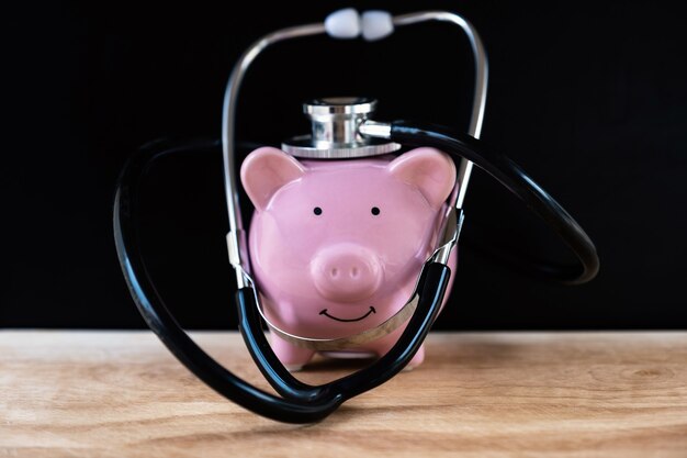 A piggy bank with a stethoscope resting on it, symbolizing the importance of financial health and saving for unexpected medical or emergency expenses.