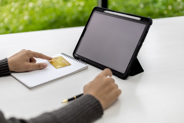 A close-up of a hand pointing to a specific error within a credit report displayed on a tablet, with a pen and paper beside it, ready to take notes.