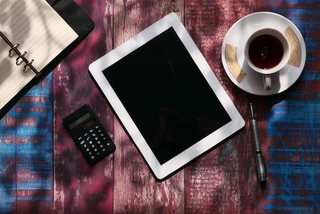 A person using a refinance calculator app on their tablet, surrounded by financial documents and a cup of coffee.