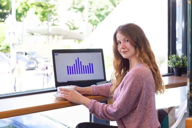 A person looking at a graph that shows an upward trend, smiling. The background shows a laptop and financial reports, suggesting analysis and positive investment outcomes.